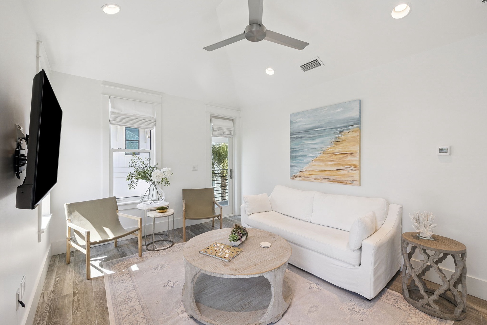 Your bright living space features a plush white sofa and coastal artwork, perfect for relaxing after beach adventures.