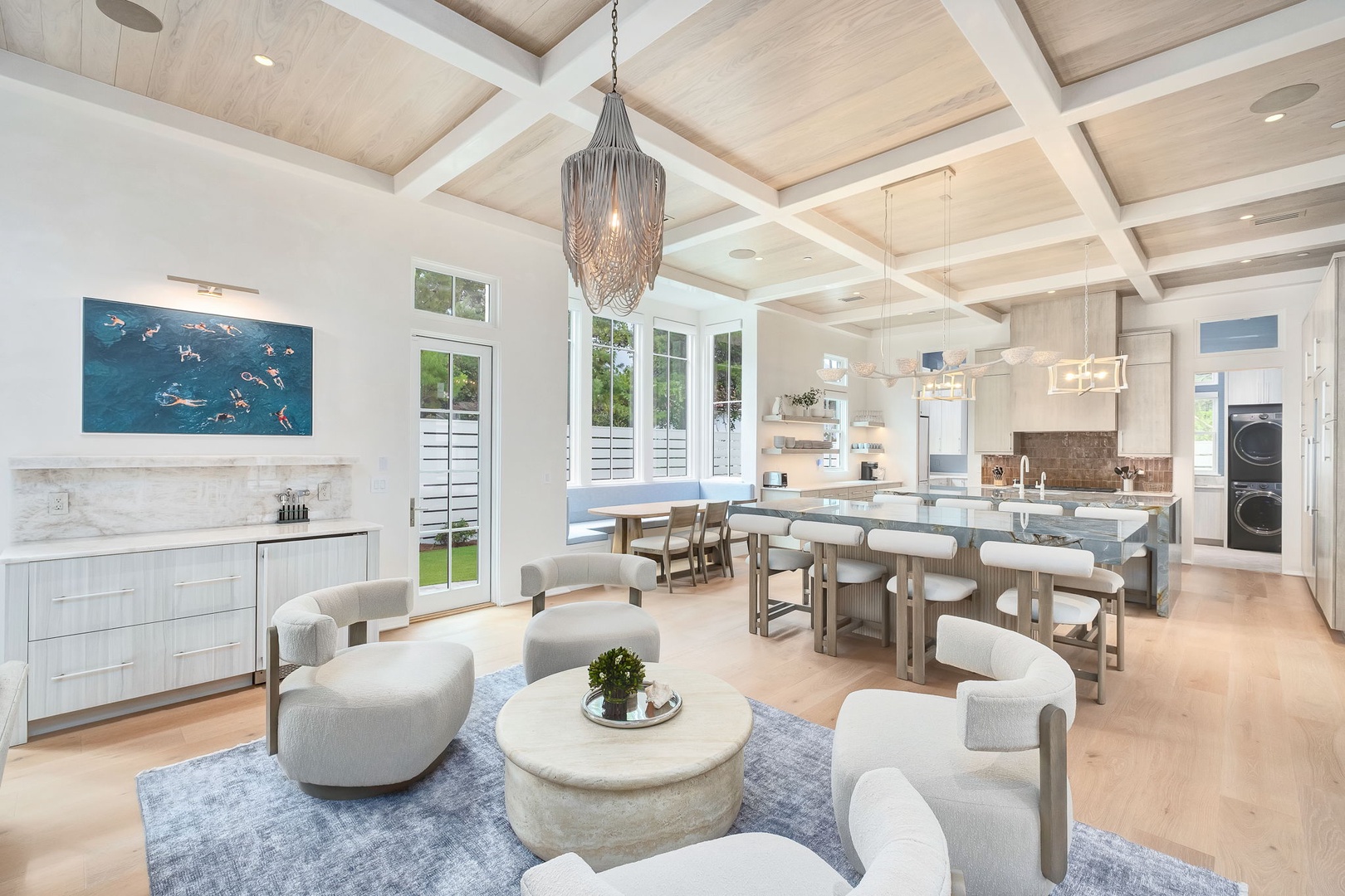 Relax in your open-concept living space, where soaring wood-beamed ceilings, coastal charm, and thoughtfully designed seating blend seamlessly with a chef's kitchen—perfect for gathering and unwinding together.