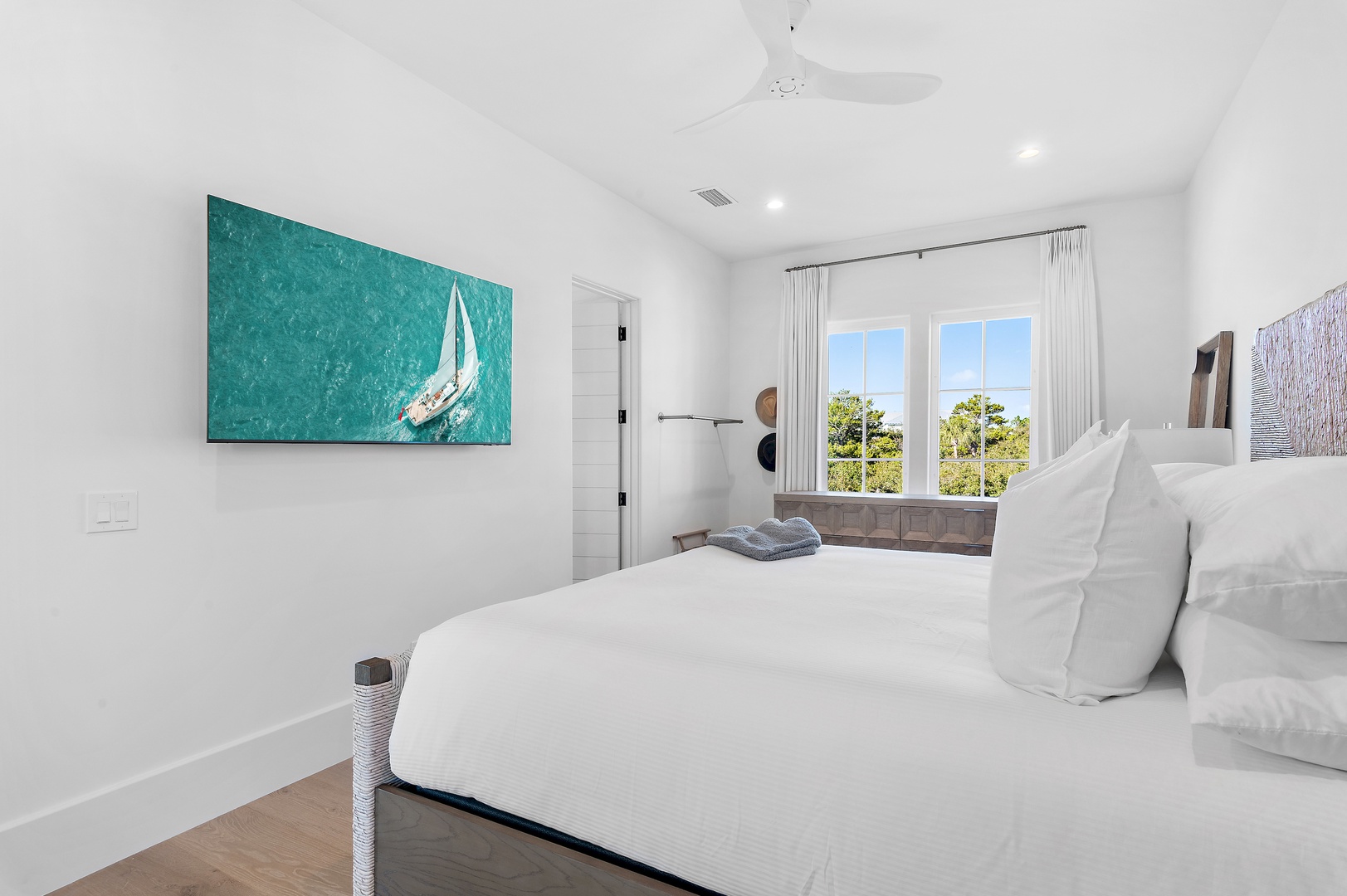 Drift off beneath coastal artwork and crisp linens, your window framing greenery that promises peaceful mornings and quiet evenings in this serene retreat.