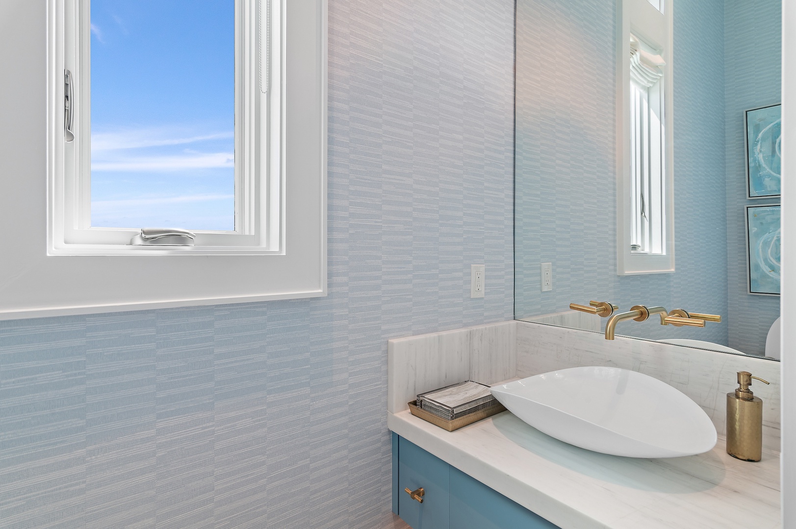 Freshen up in your serene coastal-inspired bathroom, where soft blue tones and elegant gold fixtures create a spa-like atmosphere perfect for unwinding after a day of adventure.
