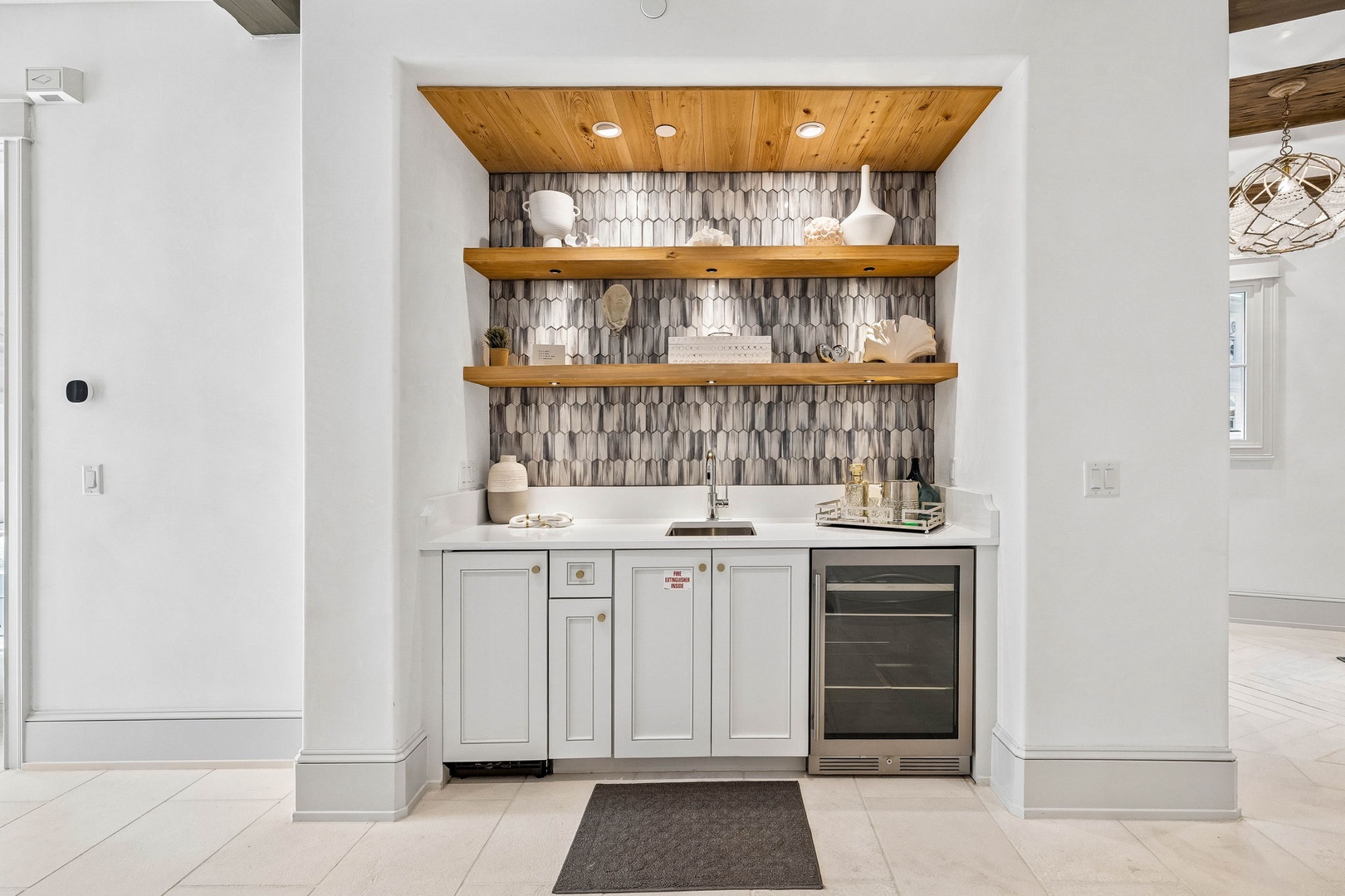 Your stylish wet bar nook features geometric tile, warm wood shelving, and a beverage fridge—perfect for pouring a drink and unwinding after exploring.