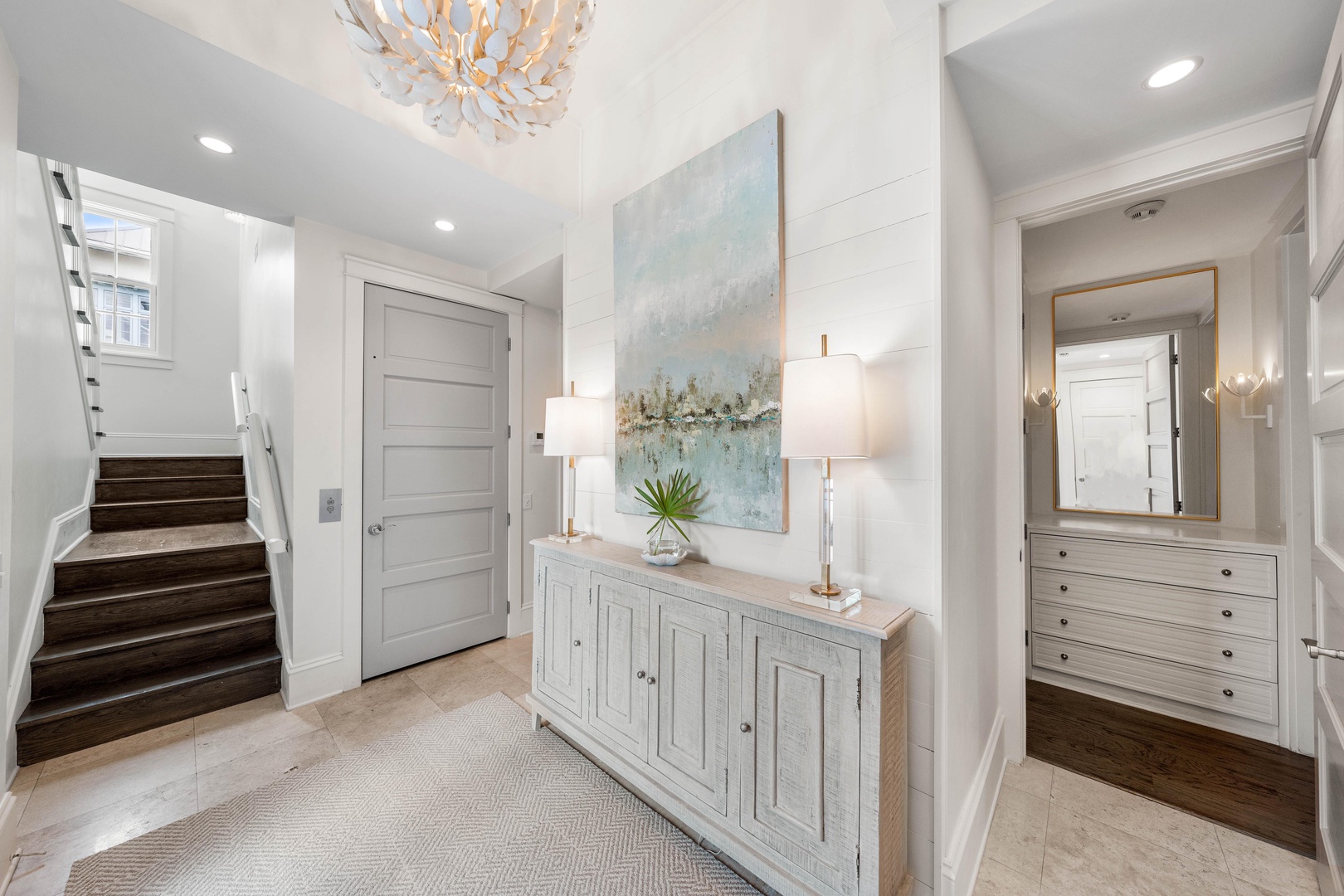 Step into your elegant entryway where coastal artwork and sophisticated lighting create the perfect welcome home atmosphere.
