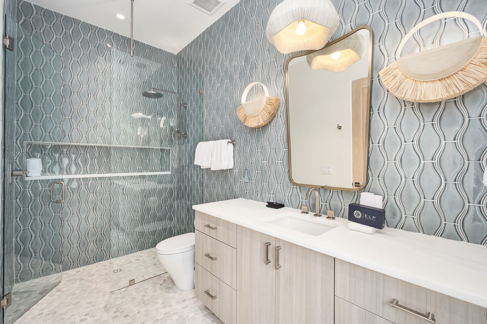 Step into your spa-like ensuite, where soothing blue-gray tiled walls and warm natural wood vanity create a tranquil coastal retreat perfect for unwinding after sun-soaked days.