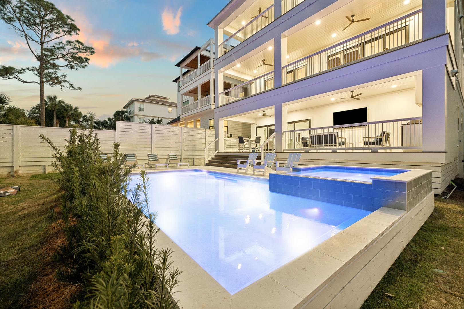 Modern vacation home featuring a stunning private pool area with illuminated blue waters and spacious outdoor entertainment zones.