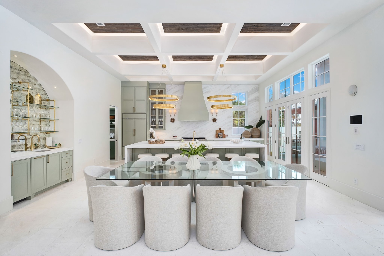 Gather around a bright, elegant kitchen where marble and gold accents frame your culinary adventures, and natural light pours in through expansive French doors—ready to inspire your best meals.