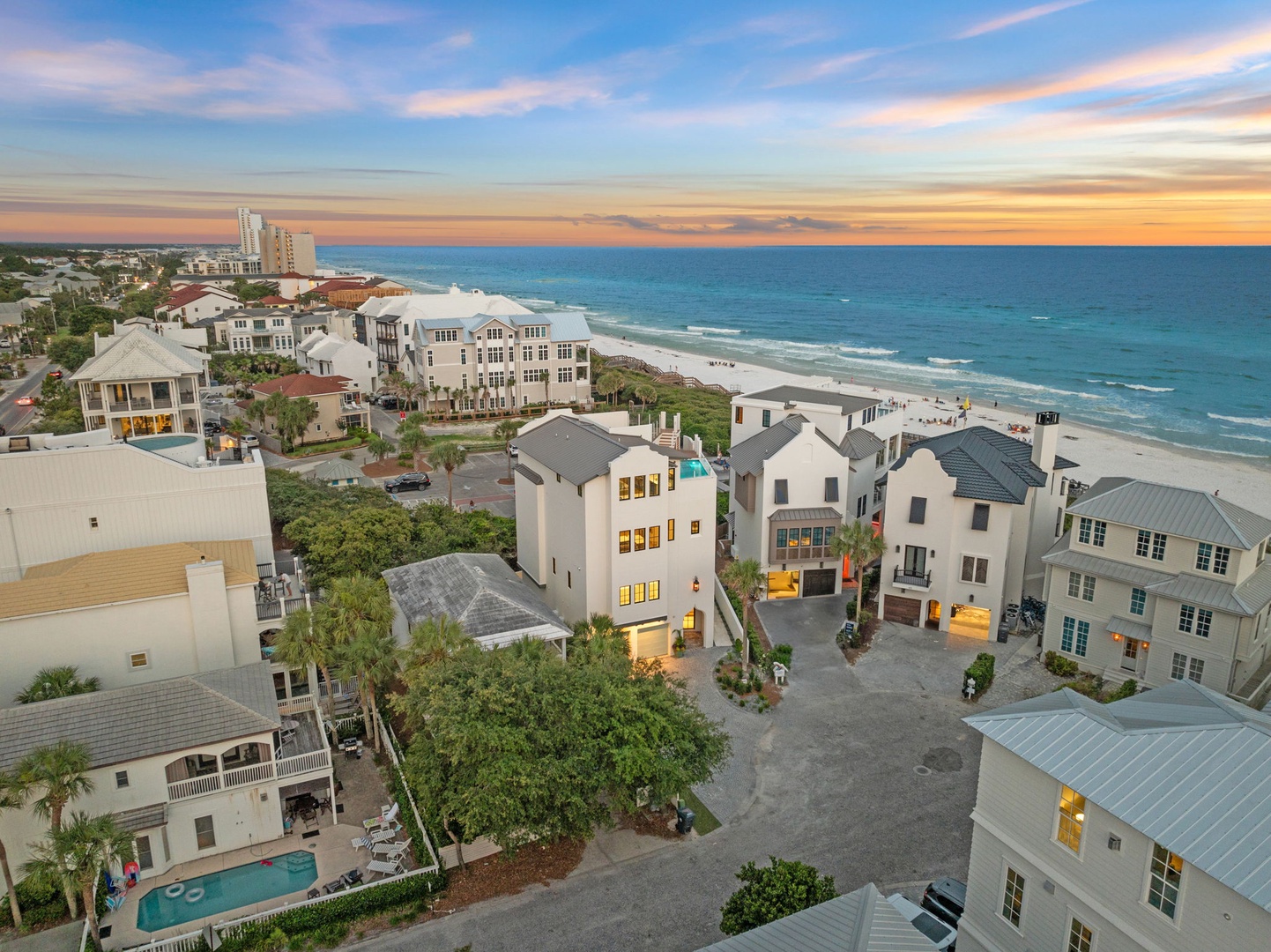 Aerial view of a coastal vacation community at sunset, showcasing beachfront properties, residential buildings, and pristine white sand beaches along the Gulf Coast.