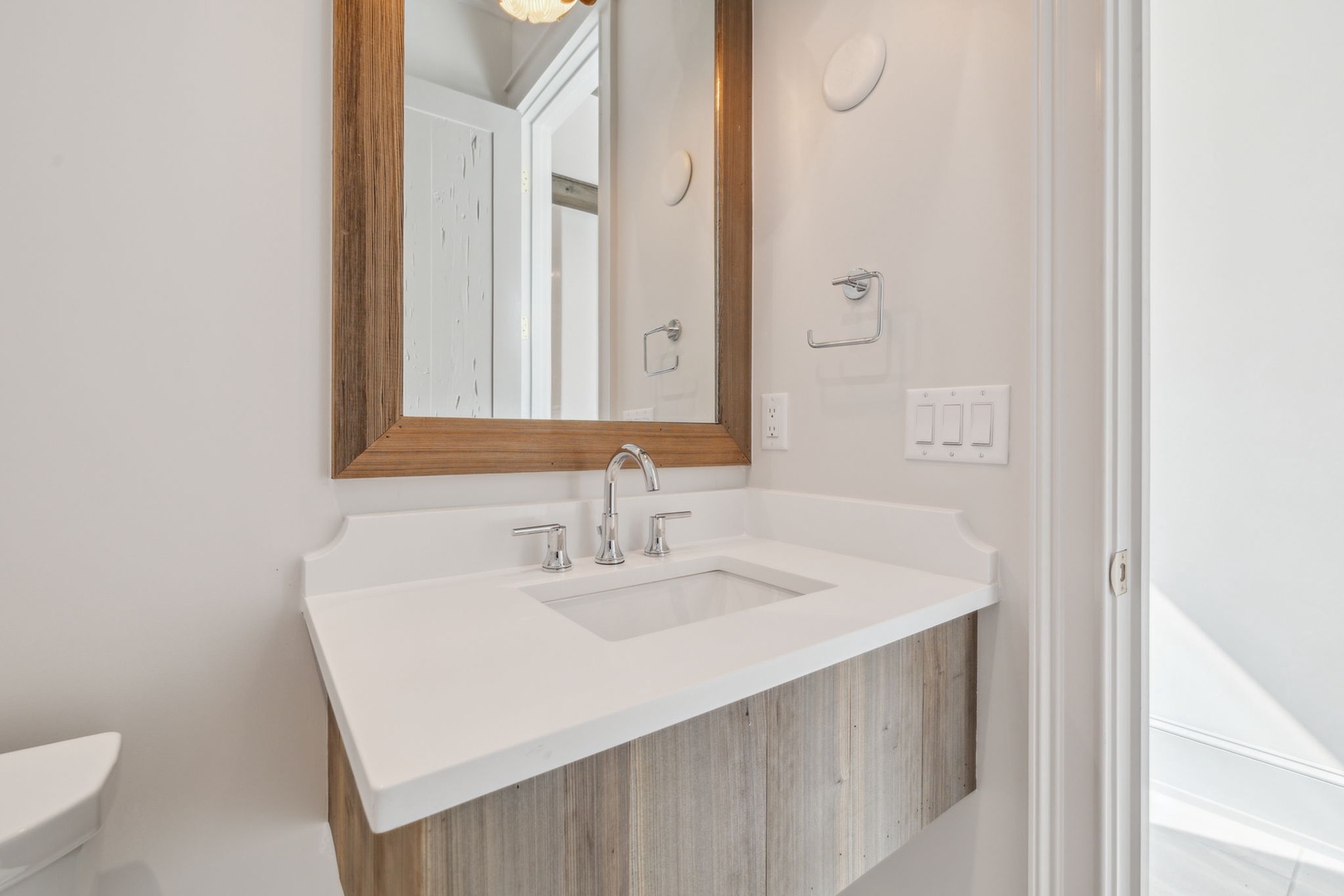 Step into your serene bathroom featuring a beautiful vanity with white quartz countertops and warm wood accents that create a coastal-inspired retreat.