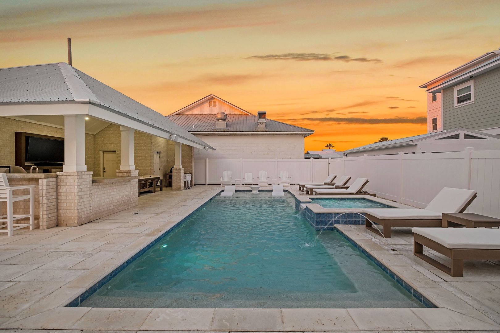 Stunning sunset backdrop frames this private pool oasis with outdoor kitchen and loungers for perfect evening relaxation.