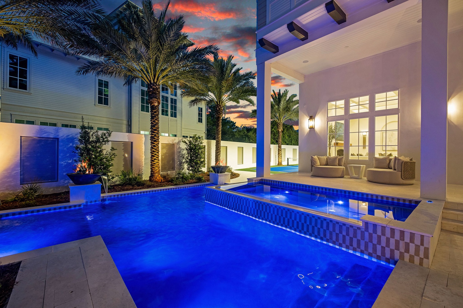 The stunning pool glows under the evening sky, framed by elegant landscaping and tropical palms. Your private oasis awaits as twilight paints the horizon.
