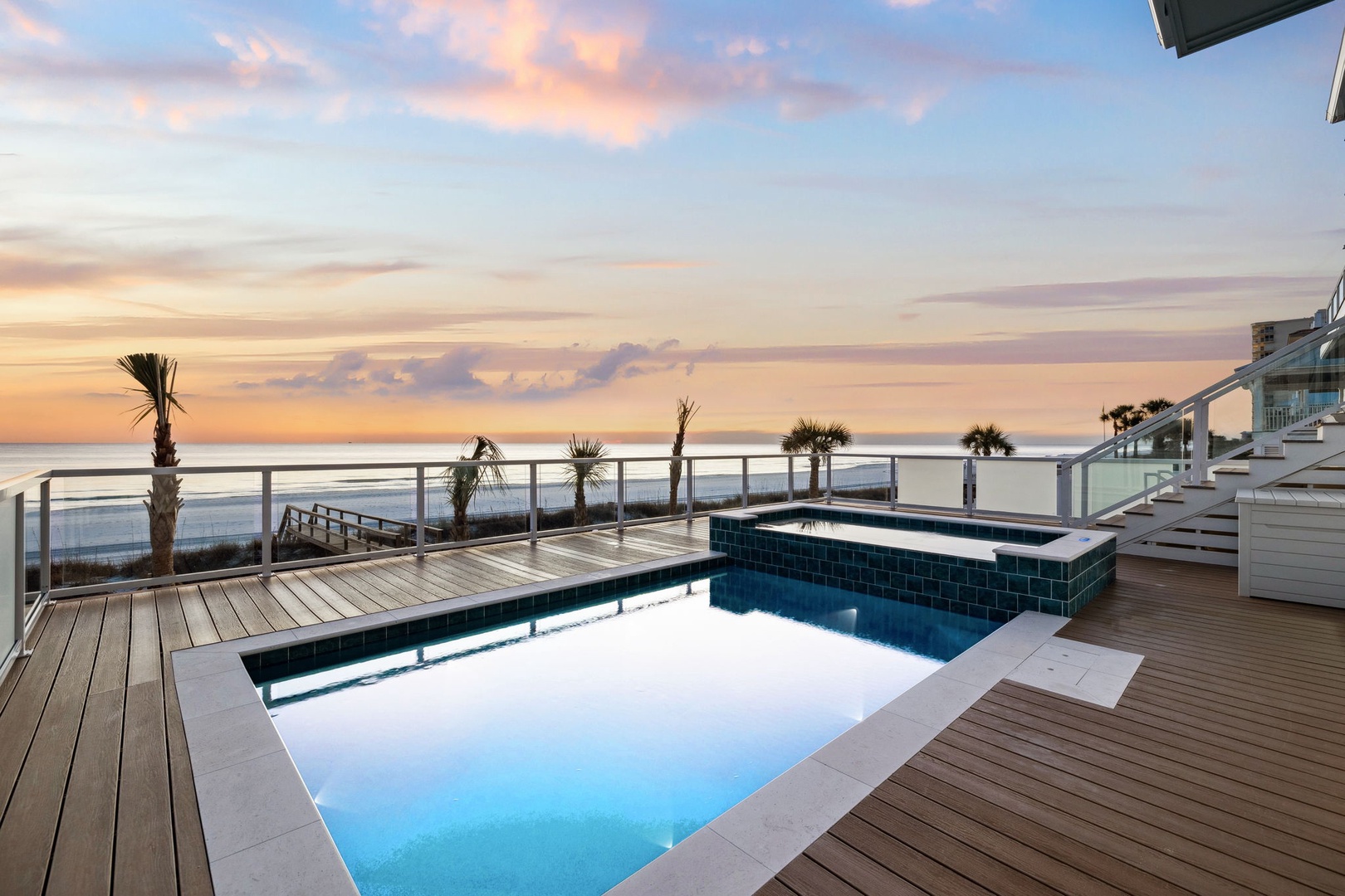 Oceanfront property with rooftop pool and hot tub overlooking the sea during golden hour.
