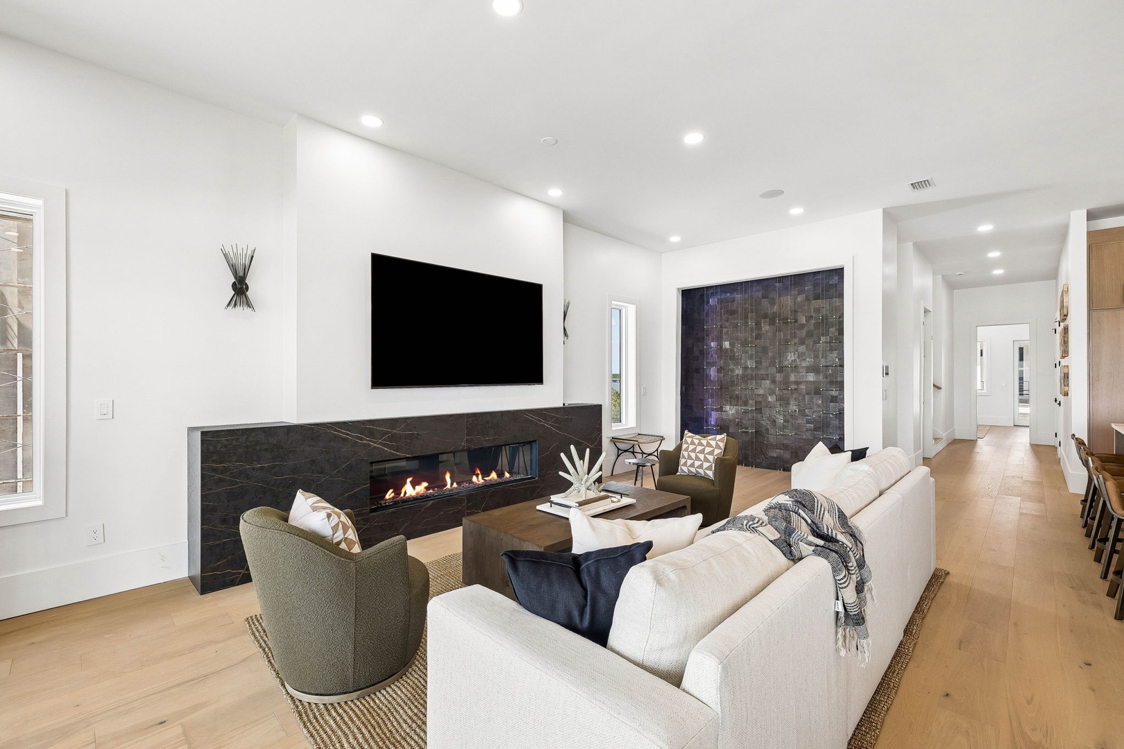 Sink into plush seating by the sleek linear fireplace, where modern elegance meets cozy warmth. This bright, open living space invites you to unwind in style.