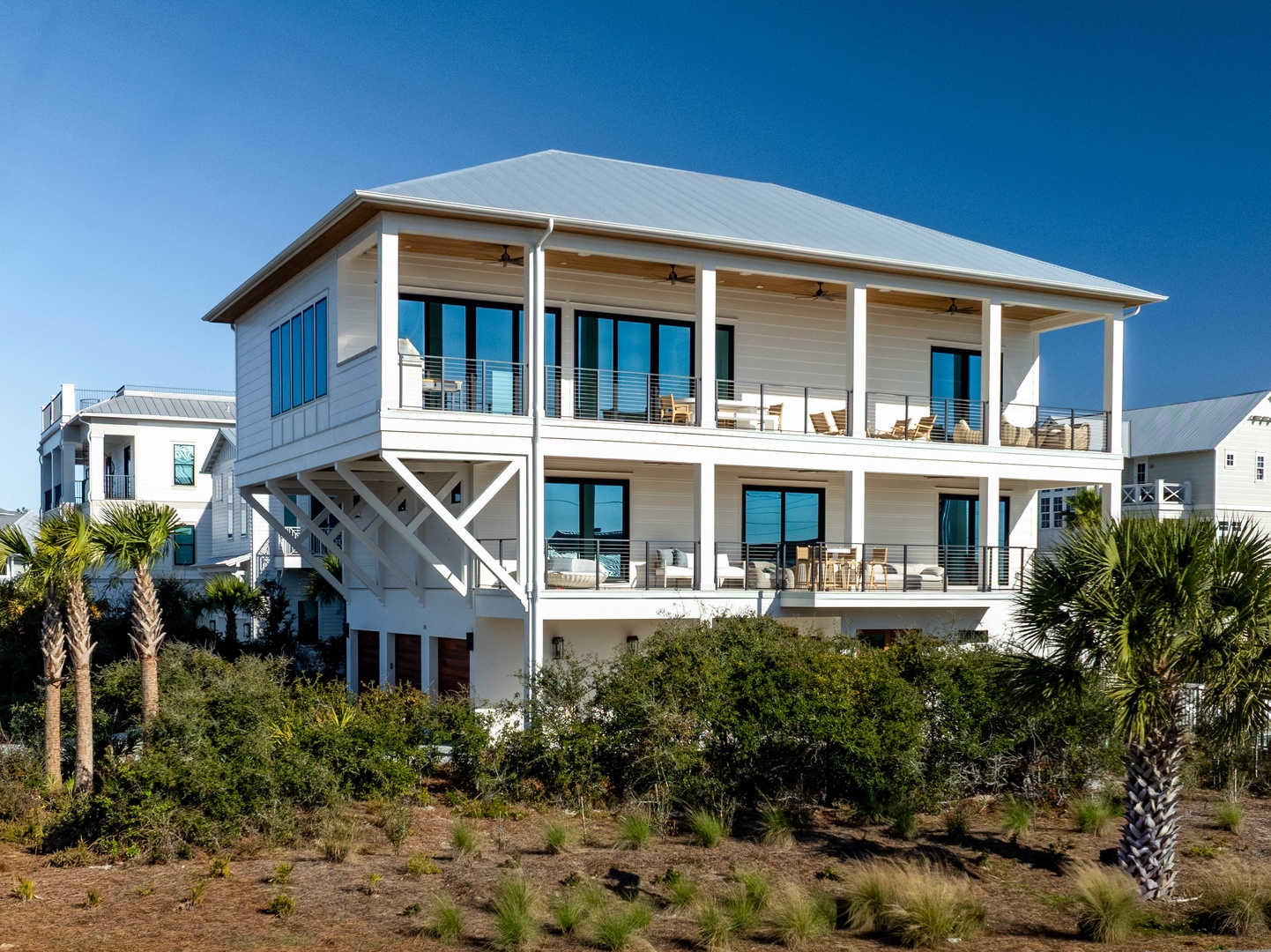 Stunning coastal beach house with elevated design and multiple covered balconies overlooking the surrounding tropical landscape.