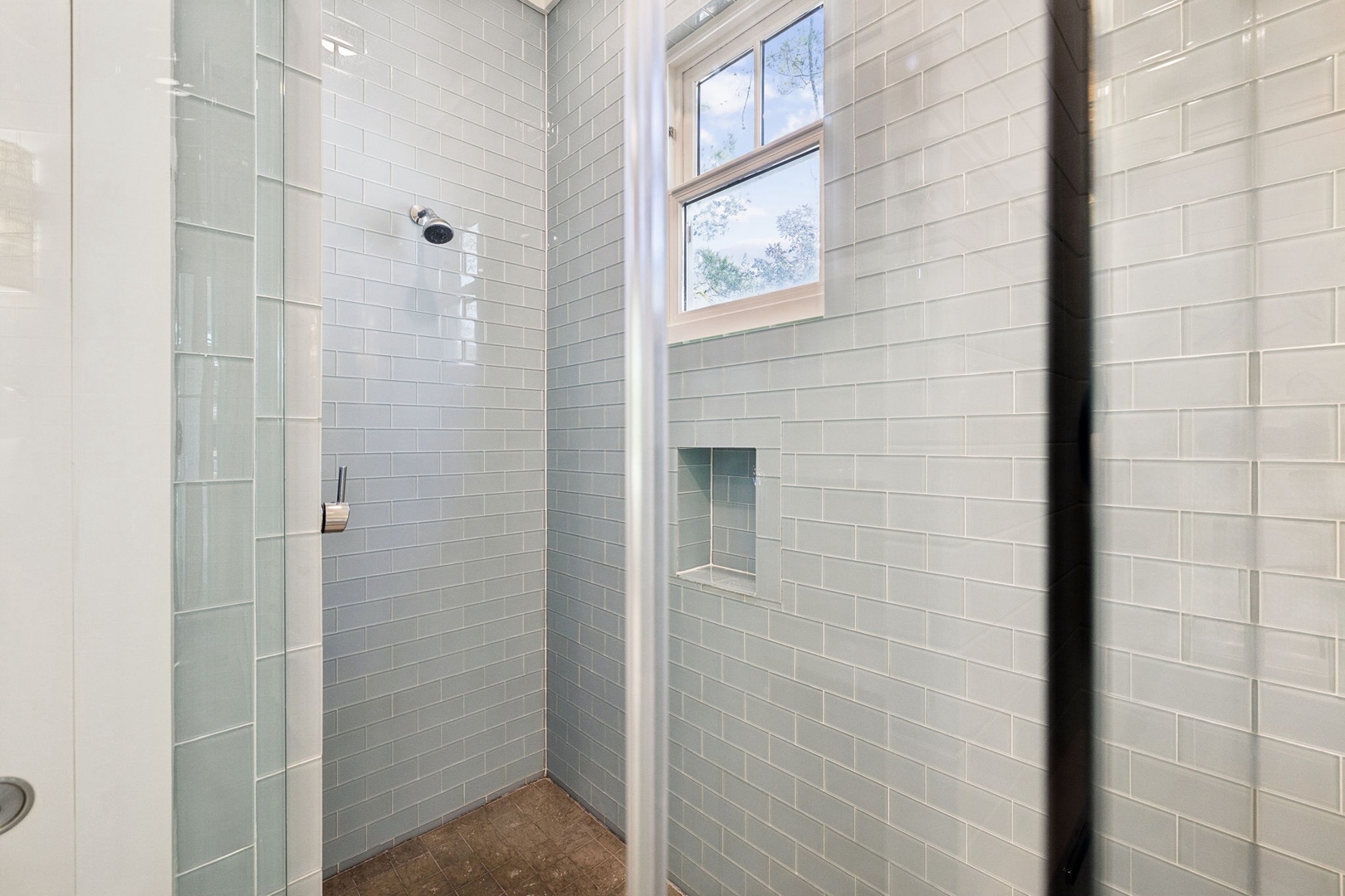 Step into your private spa-like shower with pristine subway tiles, rainfall head, and natural light streaming through.