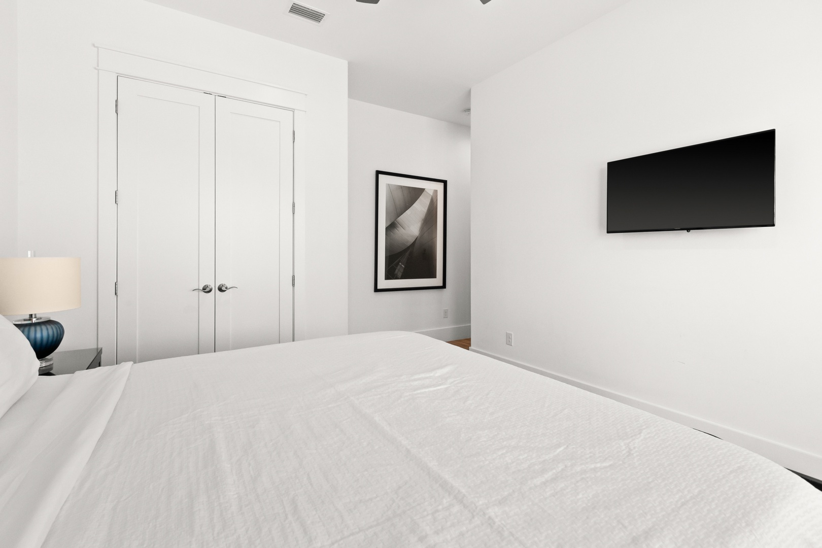 Slip into crisp linens and unwind in your serene, minimalist bedroom. Clean white walls and thoughtfully placed art set a peaceful tone, while a mounted TV lets you stream your favorites after a day of exploring.