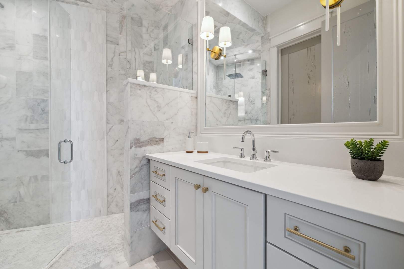 Step into your spa-like marble bathroom, where elegant fixtures and warm pendant lighting create a serene retreat. Refresh in the spacious glass-enclosed shower and enjoy the clean, modern design.