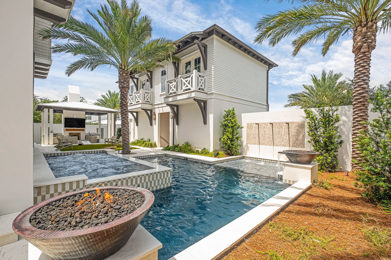 The exterior of the property showcases a welcoming multi-level structure surrounded by lush palm trees, featuring an elegant pool and spa area framed by thoughtfully designed landscaping and modern outdoor entertaining spaces.