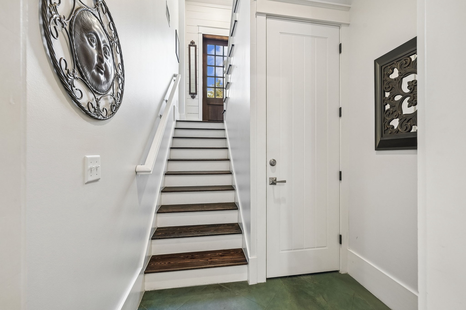 Step into your coastal retreat where rustic wood stairs lead you upward toward bright natural light and charming architectural details that make this home uniquely inviting.