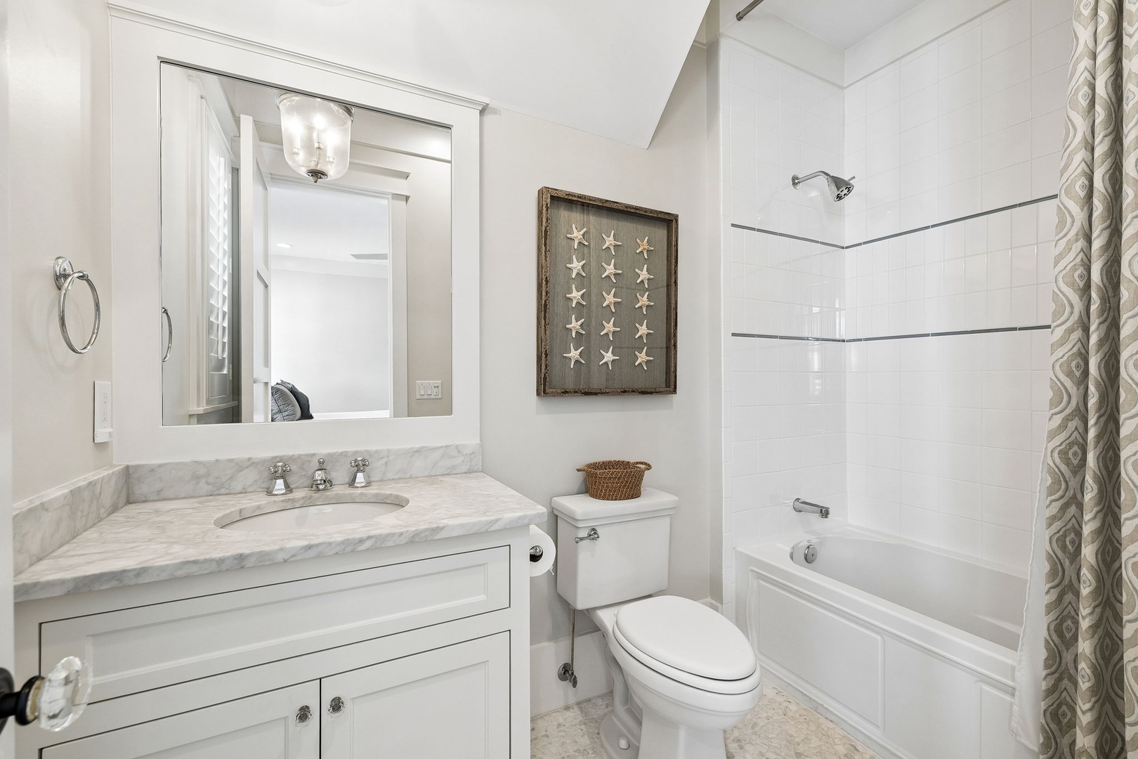 Freshen up in this bright, coastal-inspired bathroom with a classic tub-shower combo and coastal decor touches that set a relaxing tone.