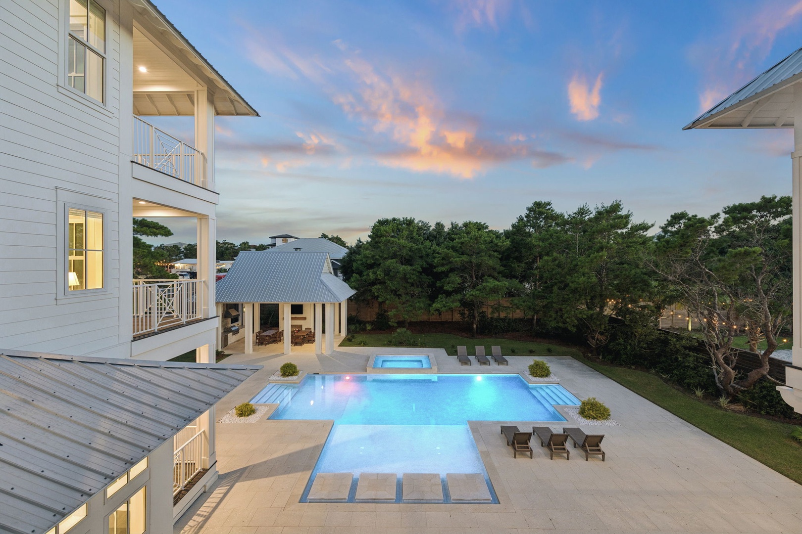 An elevated perspective of the property captures the expansive pool with built-in spa and surrounding patio as evening colors paint the sky—a serene backdrop framing your private outdoor oasis.