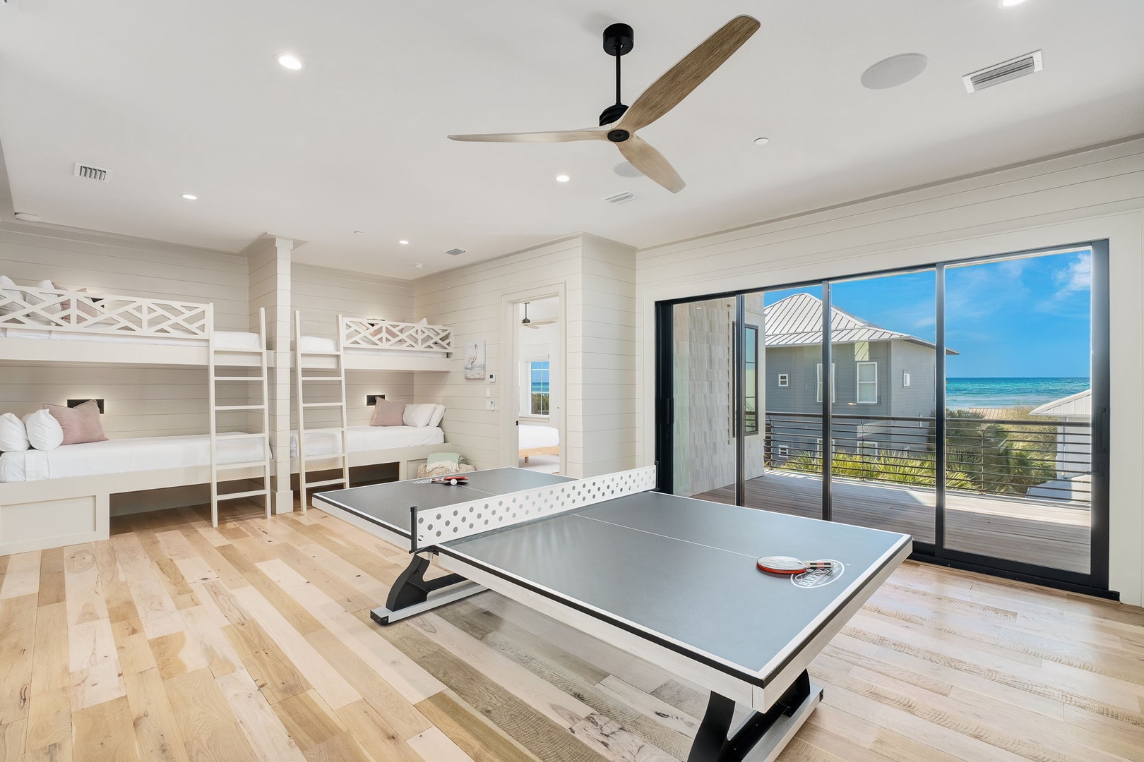 Your spacious bunk room blends rest and play with built-in beds, ping pong table, and stunning ocean views through floor-to-ceiling windows.