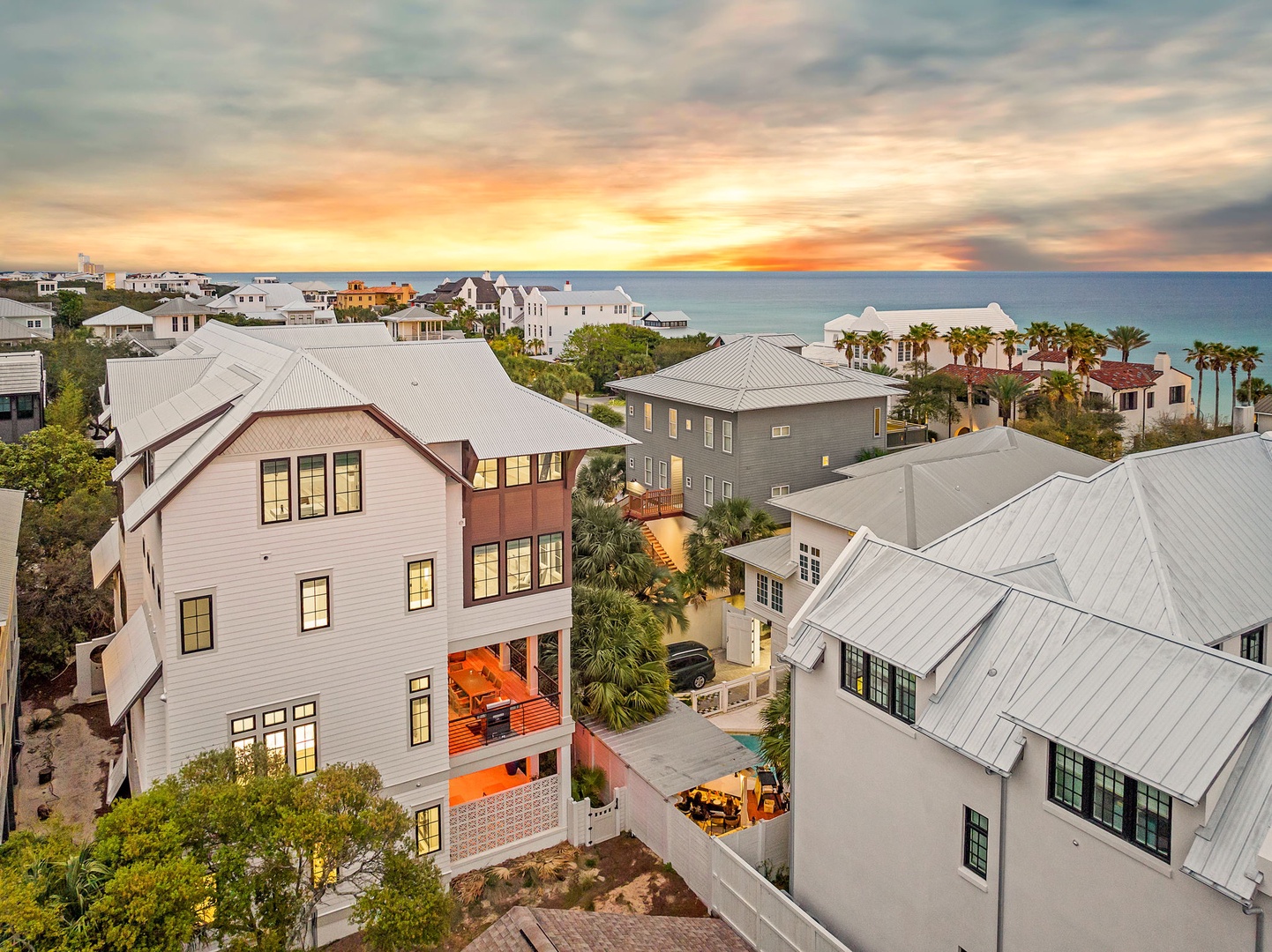 Stunning coastal community at sunset showcases beautiful beachside architecture and palm-lined streets leading to pristine turquoise waters.