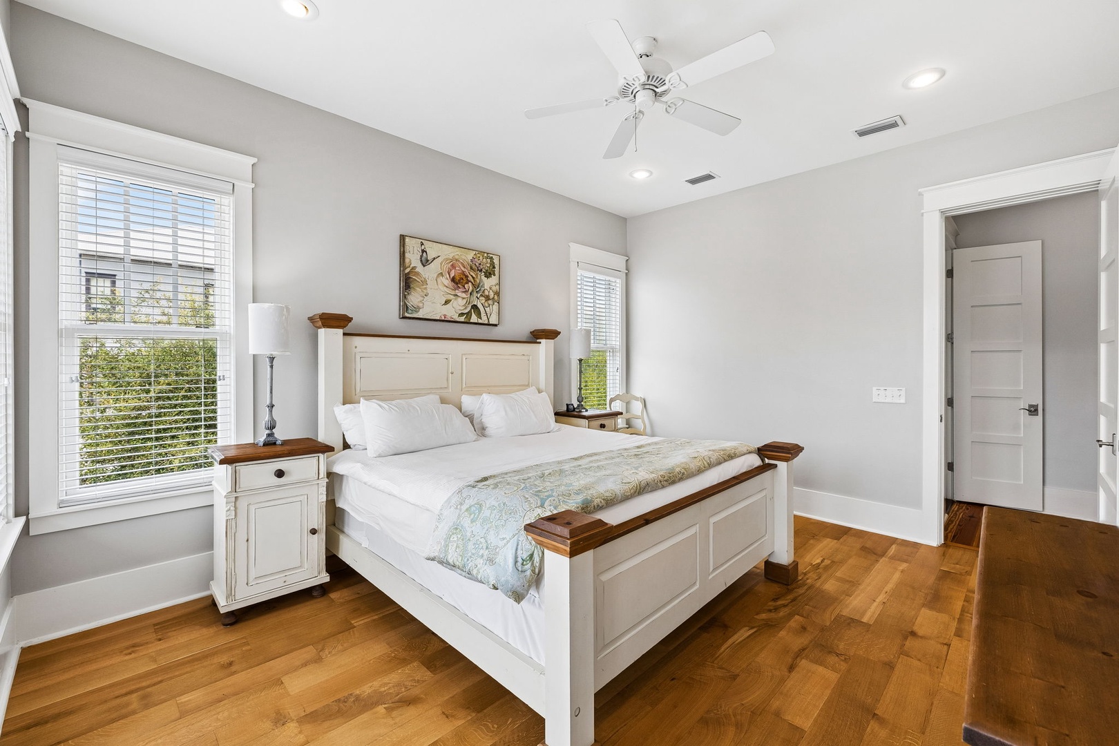 Step into your serene guest bedroom, where natural light spills across polished hardwood and a plush bed invites restful nights after exploring the area.