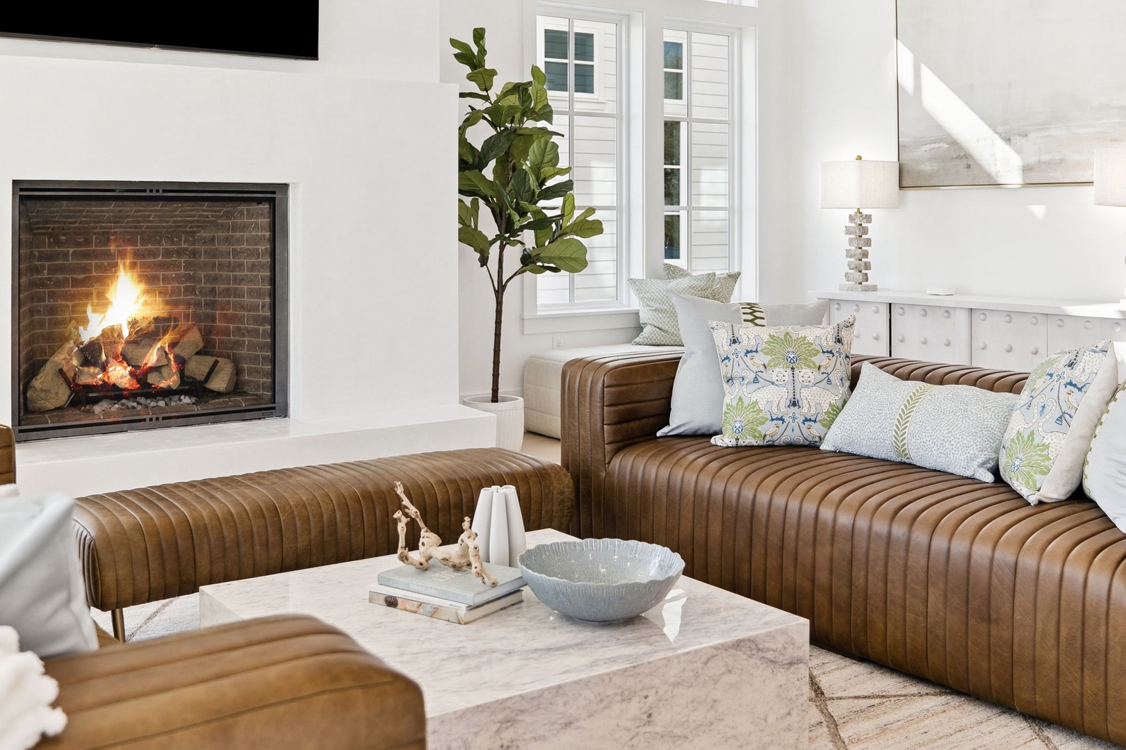 Sink into plush leather seating by your crackling fireplace, where cozy evenings unfold naturally in this elegant living space.