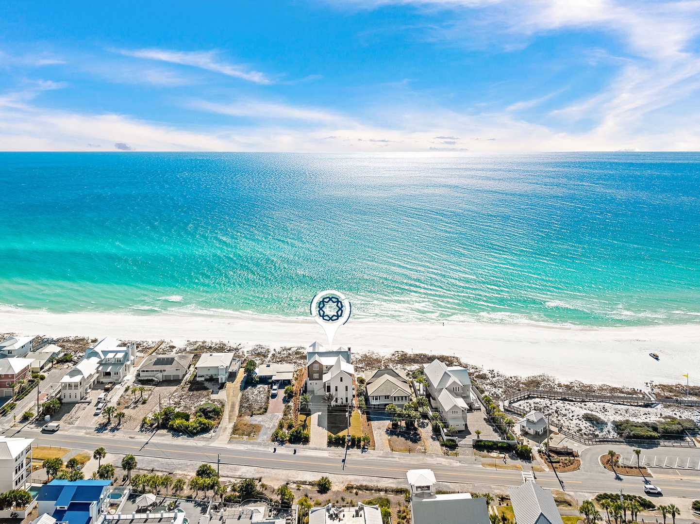 Stunning aerial view of beachfront vacation rental surrounded by pristine white sand and crystal-clear emerald waters.