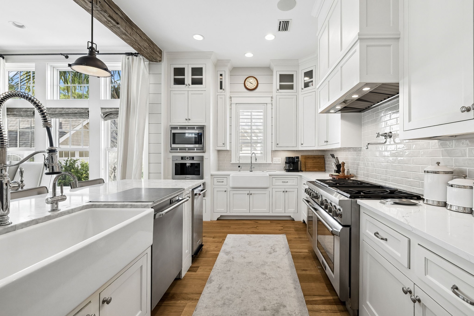 Step into your bright, coastal-inspired kitchen where crisp white cabinetry meets modern appliances and warm wood floors. Natural light pours through oversized windows, inviting you to prepare meals in this beautifully designed space.