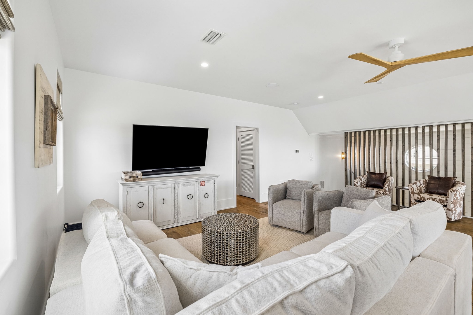 Sink into plush seating and unwind in your airy living space, where coastal-inspired textures and a warm wood ceiling fan create the perfect spot for evenings together.