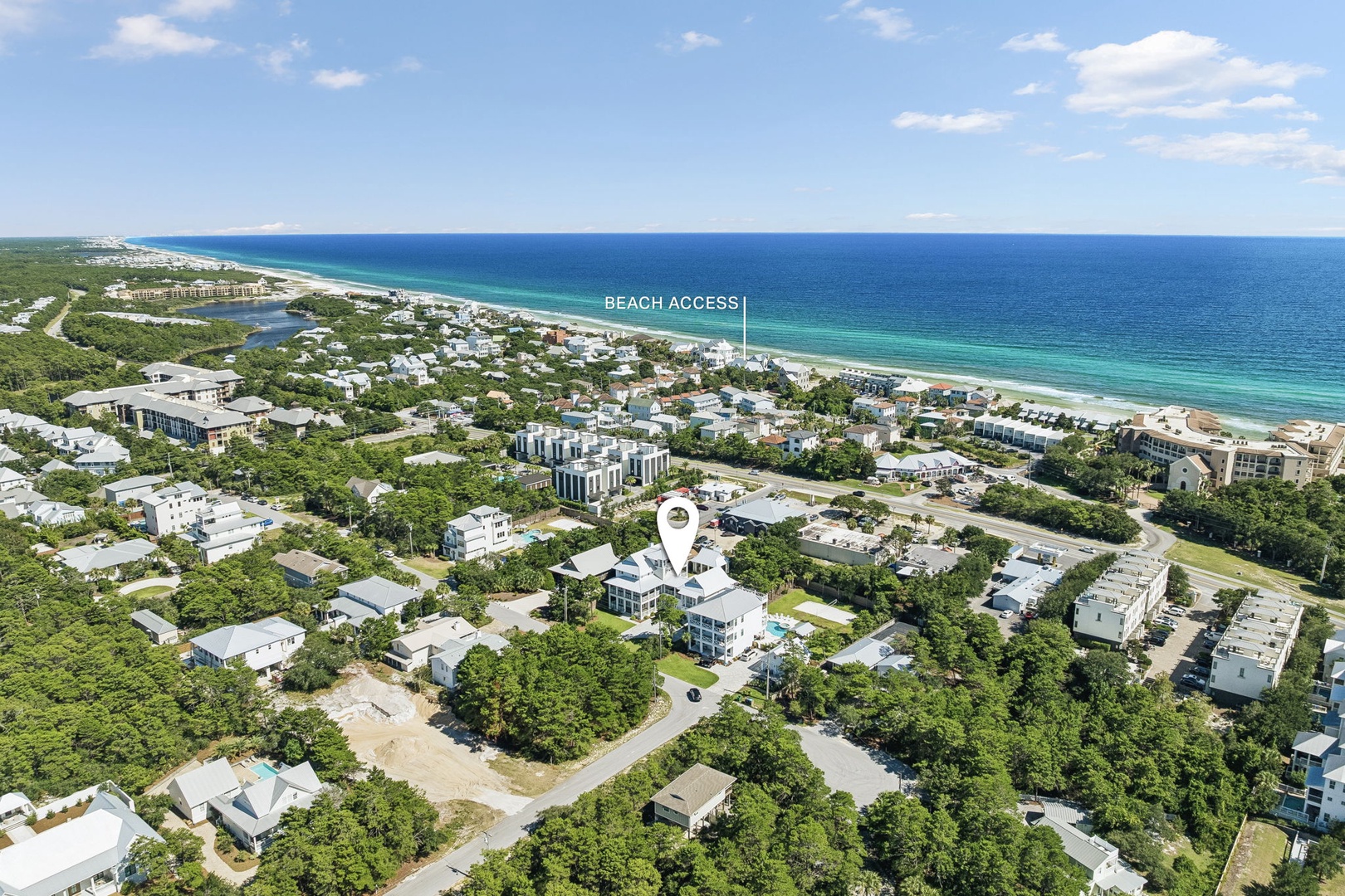 An aerial perspective showcases the coastal community stretching along turquoise waters and pristine shoreline, with tree-lined streets and residential properties dotting the landscape.
