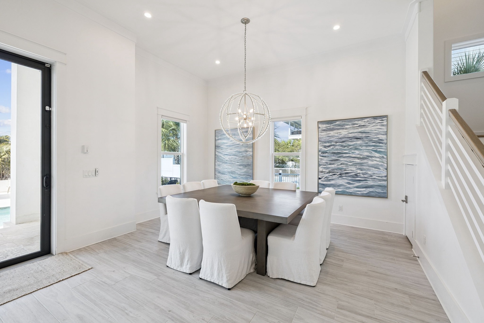 Gather around your elegant dining table beneath the stunning pendant light, where ocean-inspired artwork creates a serene backdrop for memorable meals.