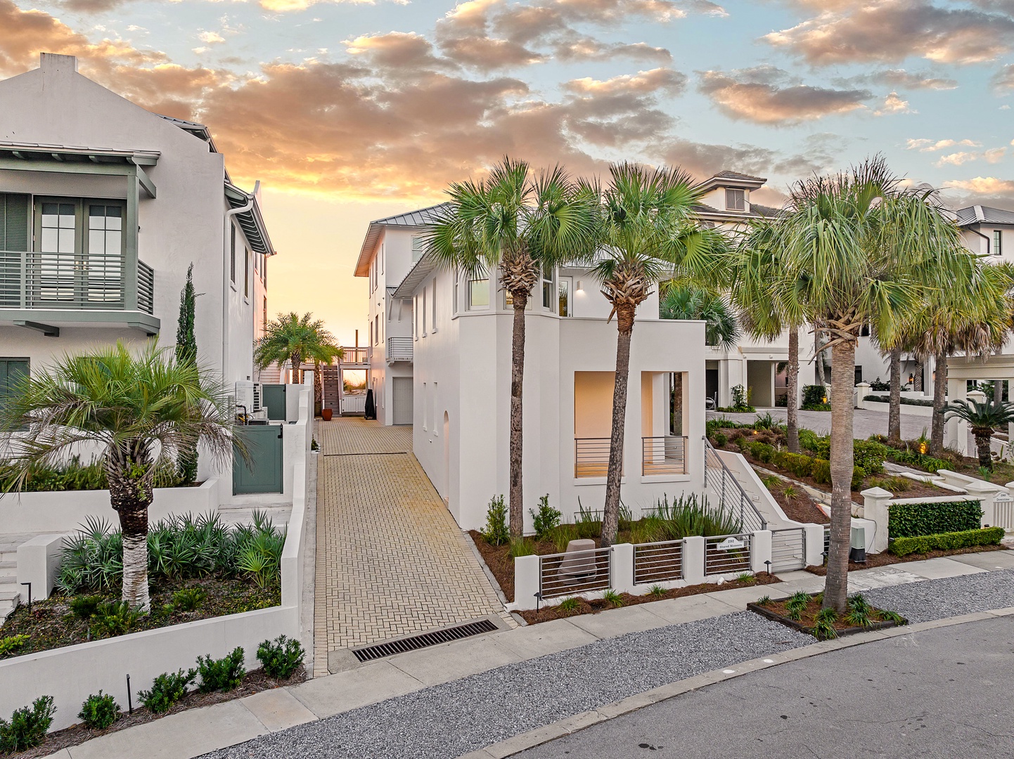 Modern coastal community featuring contemporary architecture and tropical palm landscaping under a stunning sunset sky.