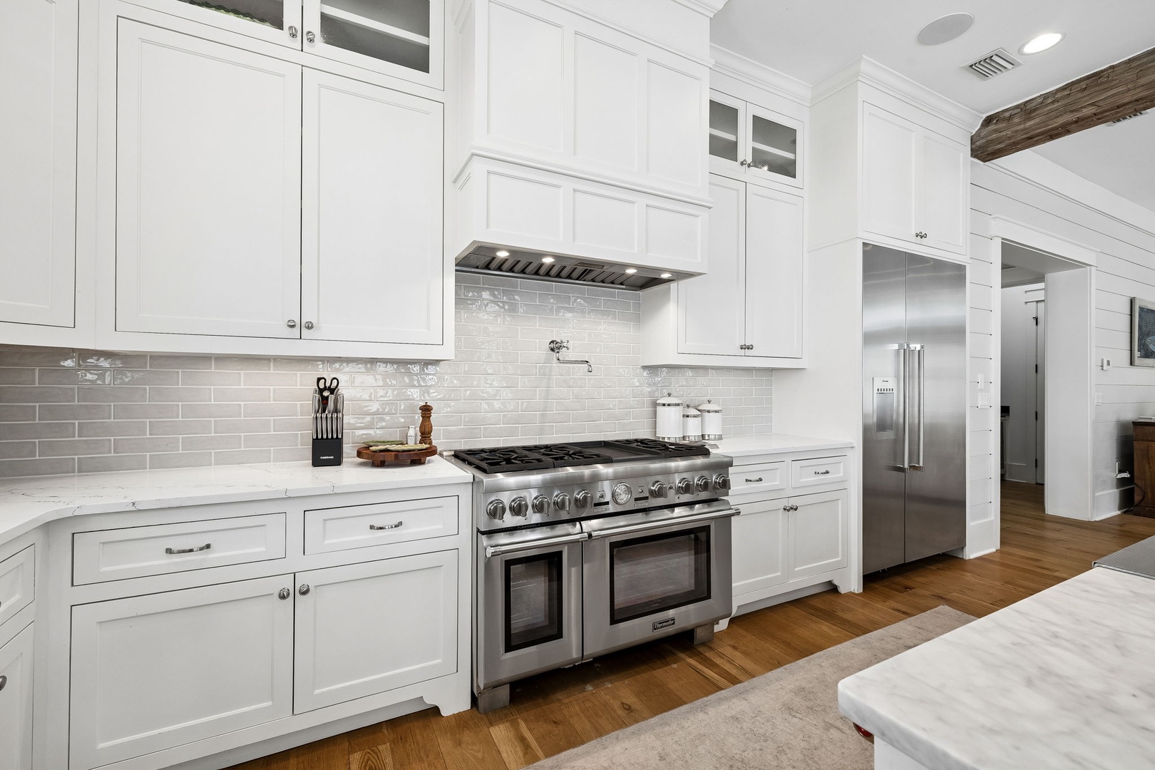 Imagine preparing your favorite meals in this bright, fully equipped kitchen, where gleaming white cabinetry meets a professional-grade range and subway-tile backsplash that reflects the natural light.