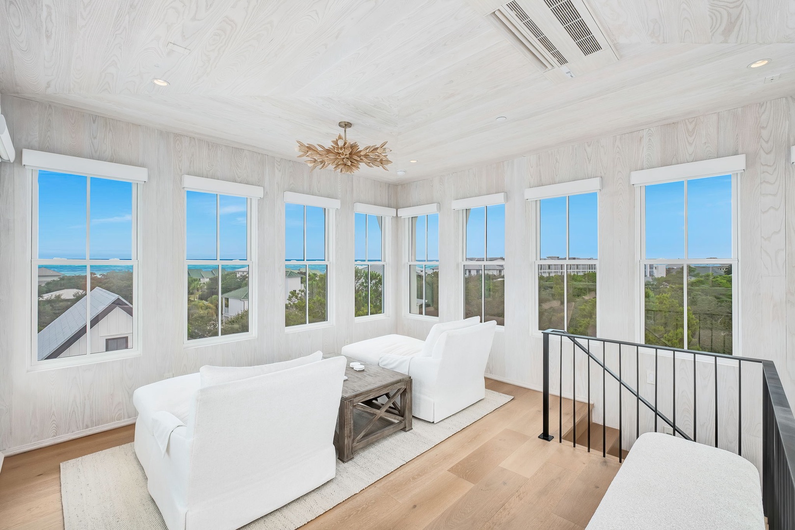 Sink into plush white seating and let your eyes wander across stunning turquoise waters and coastal greenery through floor-to-ceiling windows that wrap this light-filled retreat.