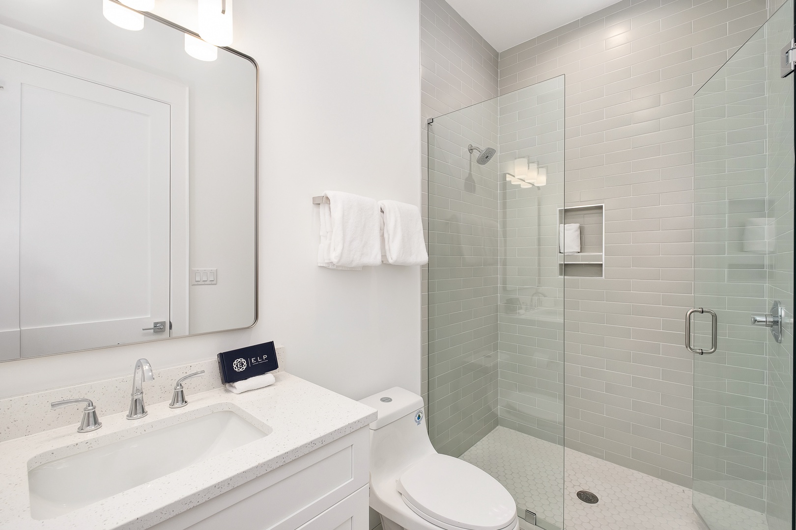 Step into your pristine bathroom featuring marble countertops, a spacious glass-enclosed shower, and crisp white linens waiting for your arrival.