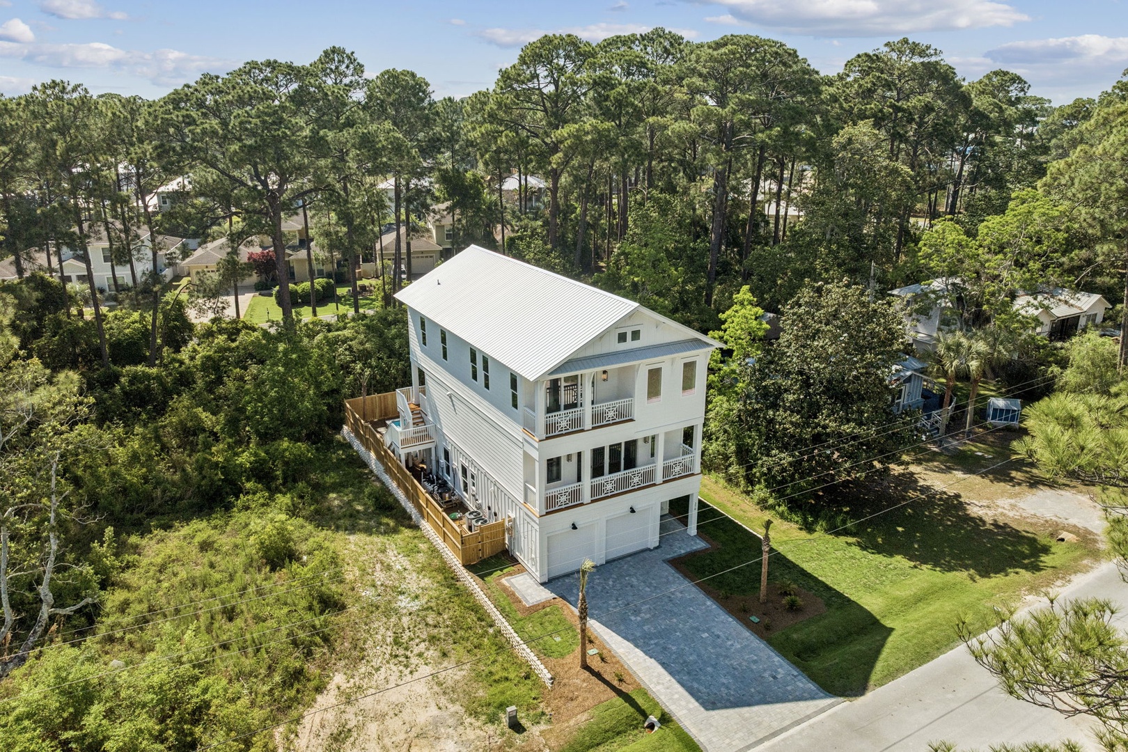 This spacious three-story coastal retreat sits peacefully on a private lot surrounded by towering pines and lush greenery, offering a serene, nature-filled setting for your getaway.