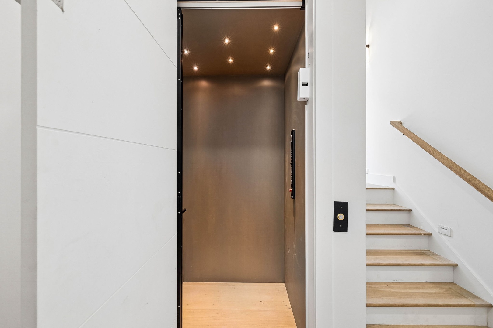 Modern elevator with soft lighting makes moving between floors effortless during your stay, while light wood stairs add a contemporary touch nearby.