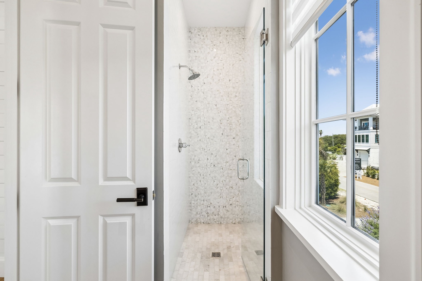 A spa-like walk-in shower with elegant tile work and a large window fills your private retreat with natural light and refreshing views.
