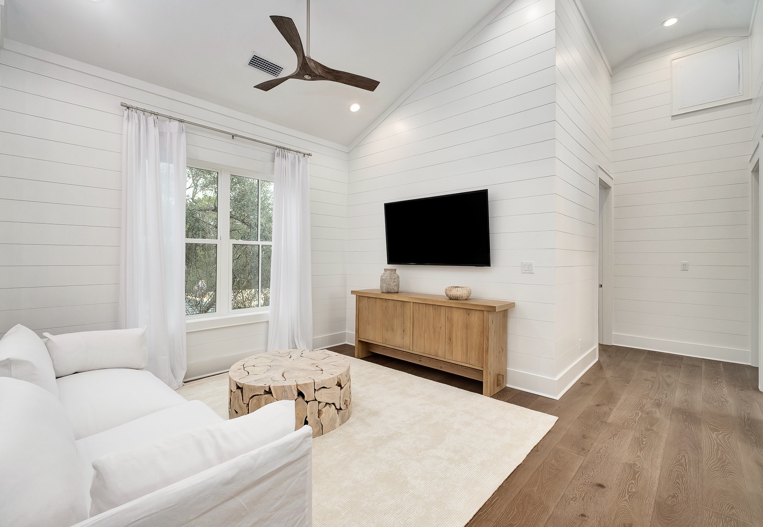 Unwind in your bright living room with shiplap walls, cozy seating, and modern entertainment for perfect relaxation.