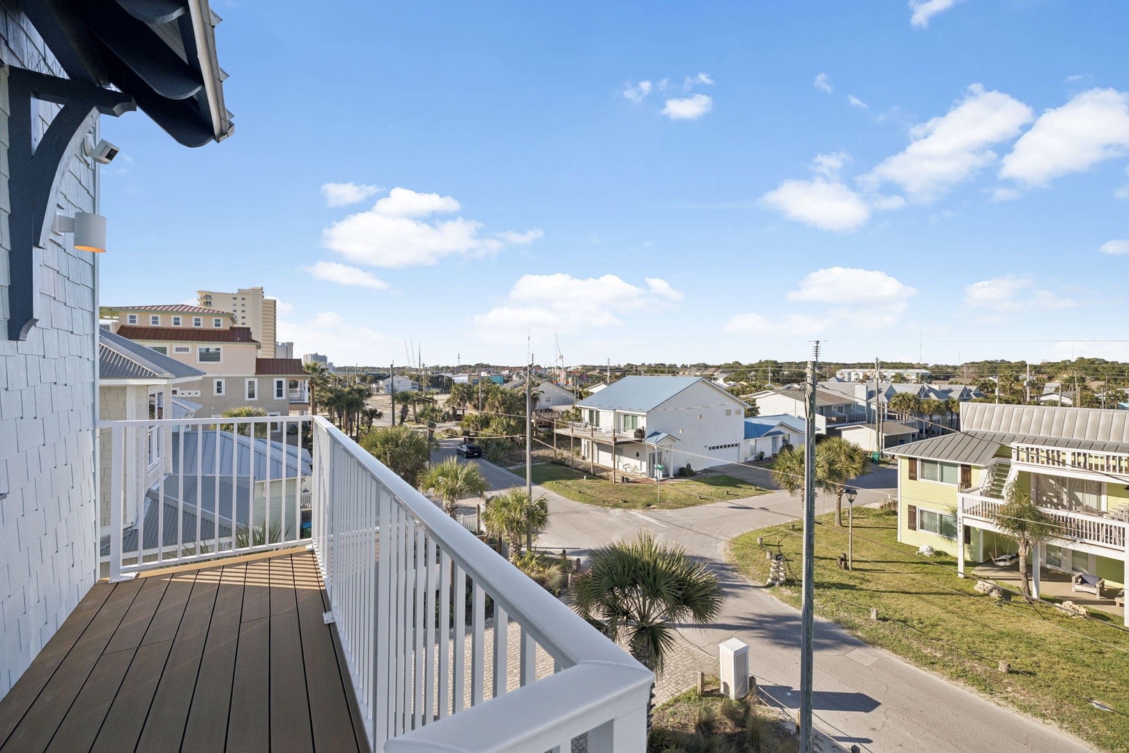 Elevated balcony overlooks a peaceful coastal neighborhood with glimpses of water in the distance.