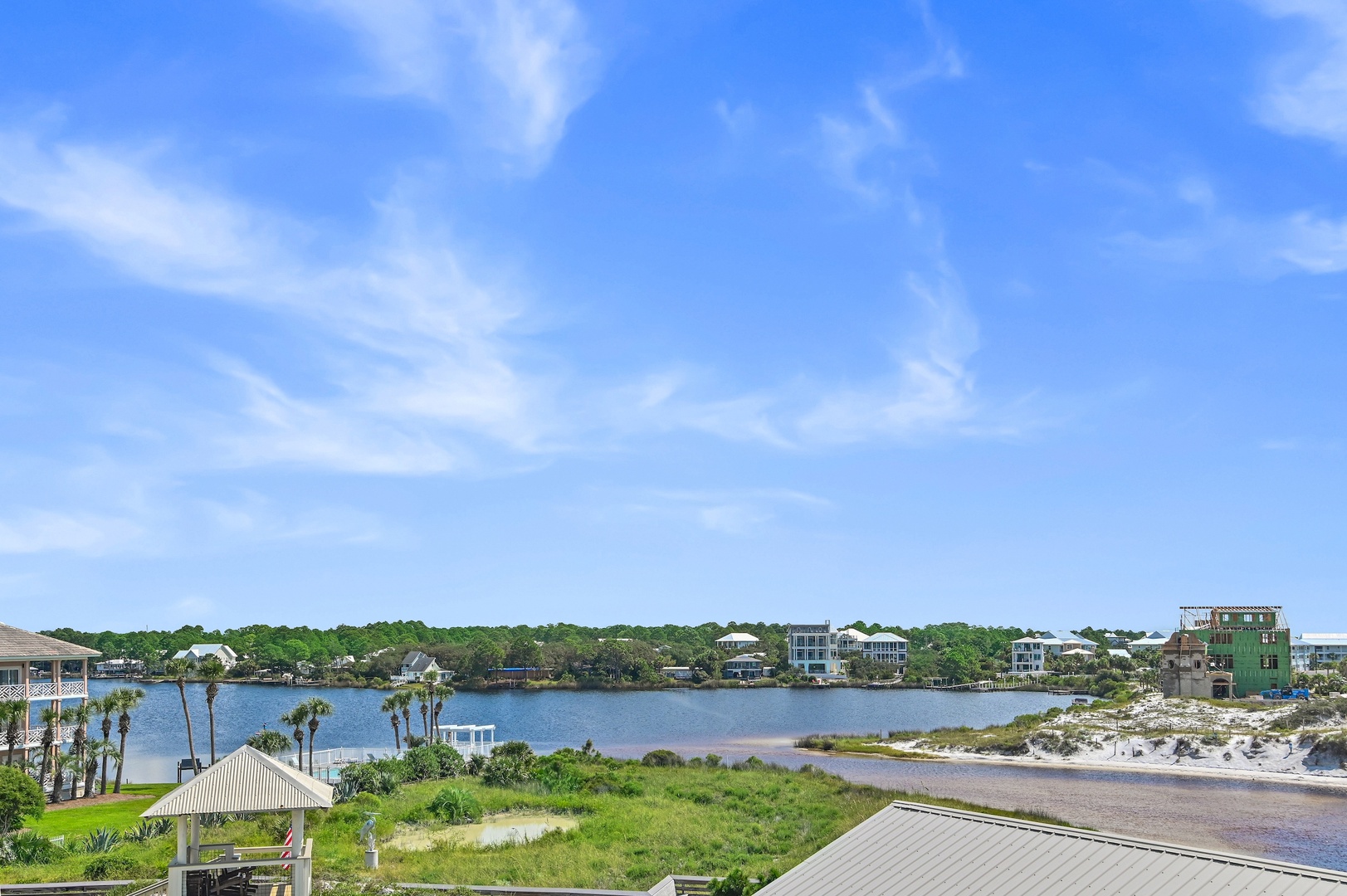 This coastal area features peaceful lagoon waters, lush vegetation, and residential properties nestled among palm trees and natural dunes.