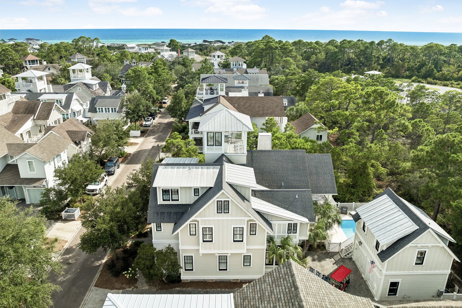 This coastal neighborhood features well-maintained homes nestled among lush vegetation, with the turquoise waters and white sand beaches visible in the distance, just moments from the property.