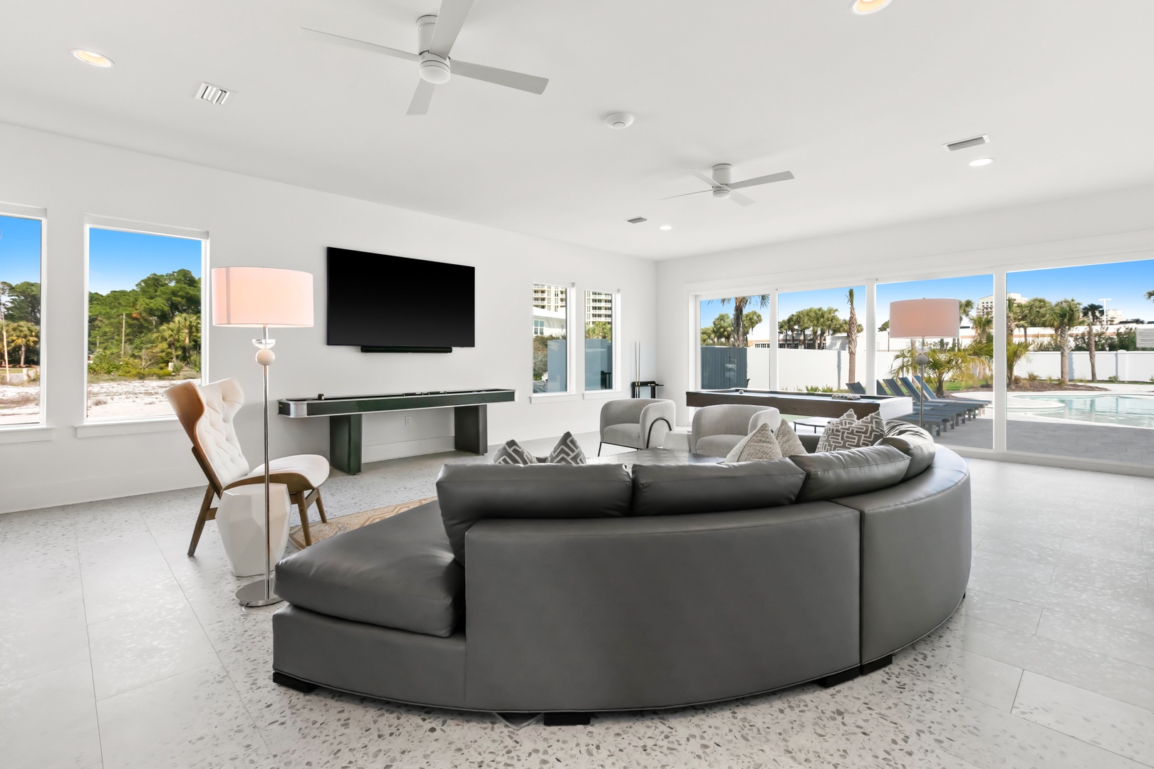 Settle into your spacious living room where the sleek curved sofa invites conversation and windows frame real palms swaying in the sunshine just outside.