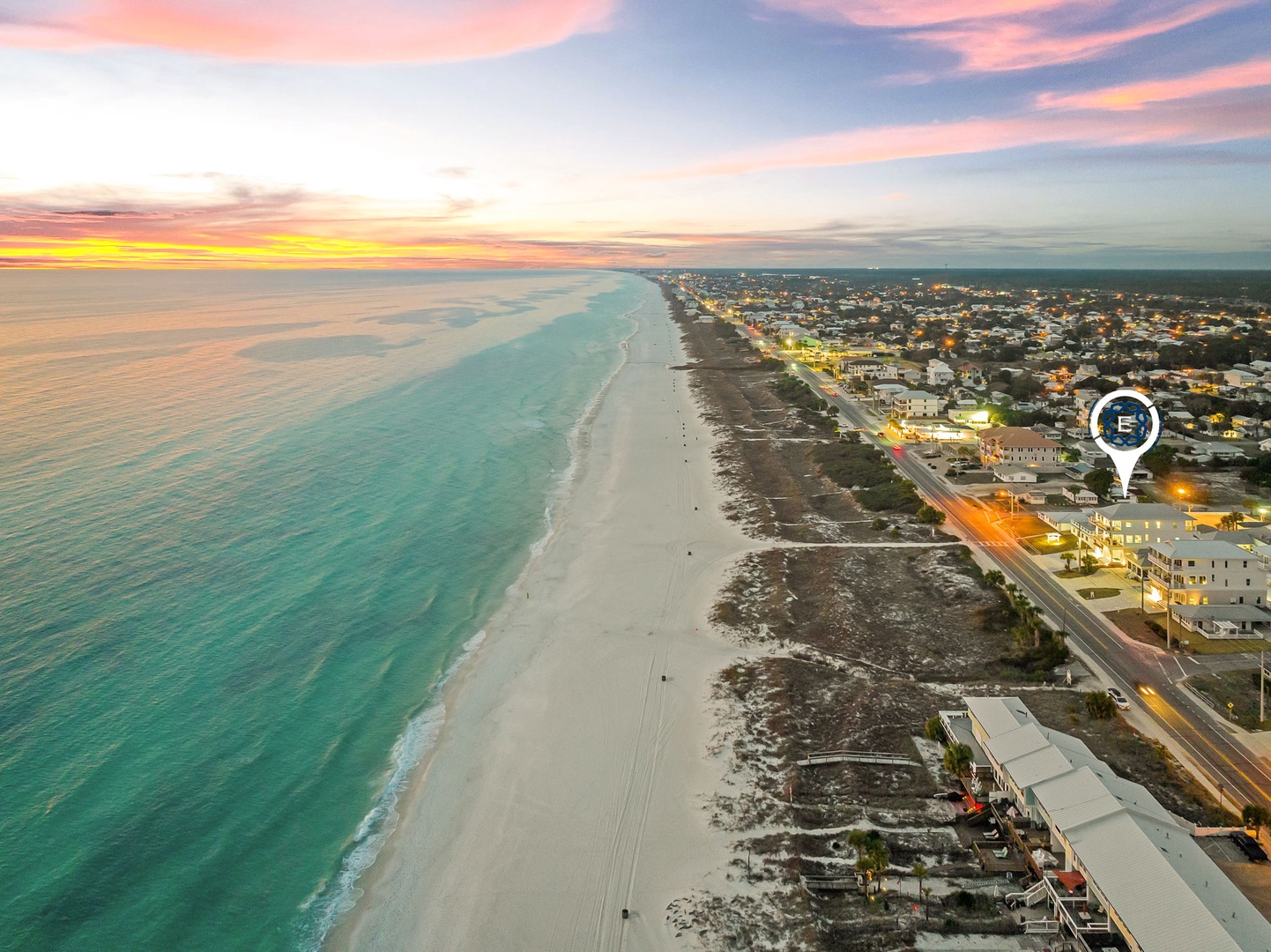 Stunning aerial view of pristine coastline with turquoise waters and white sand beach stretching along the vibrant community.