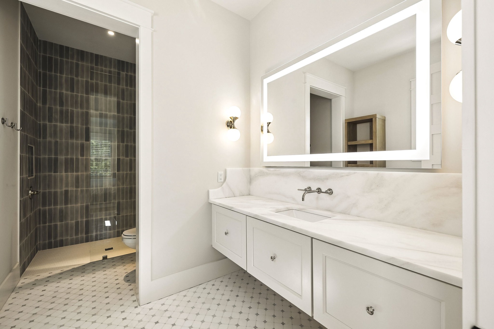 Step into your spa-like bathroom featuring sleek marble countertops, a bright LED-lit mirror, and a spacious walk-in shower with elegant charcoal tile.