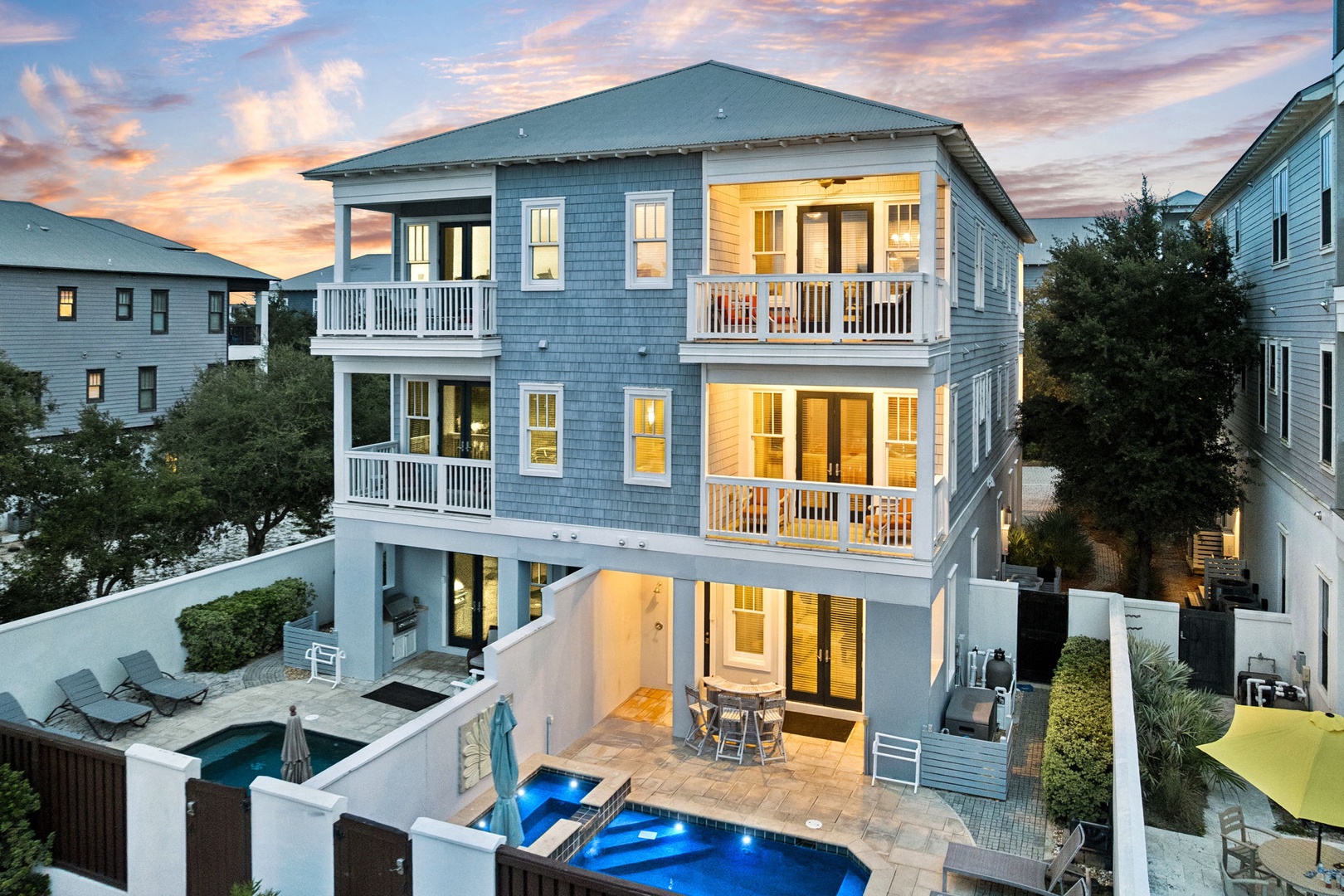 A modern three-story coastal retreat with twin balconies and private pool awaits, perfectly positioned to catch stunning sunset views over the neighborhood.