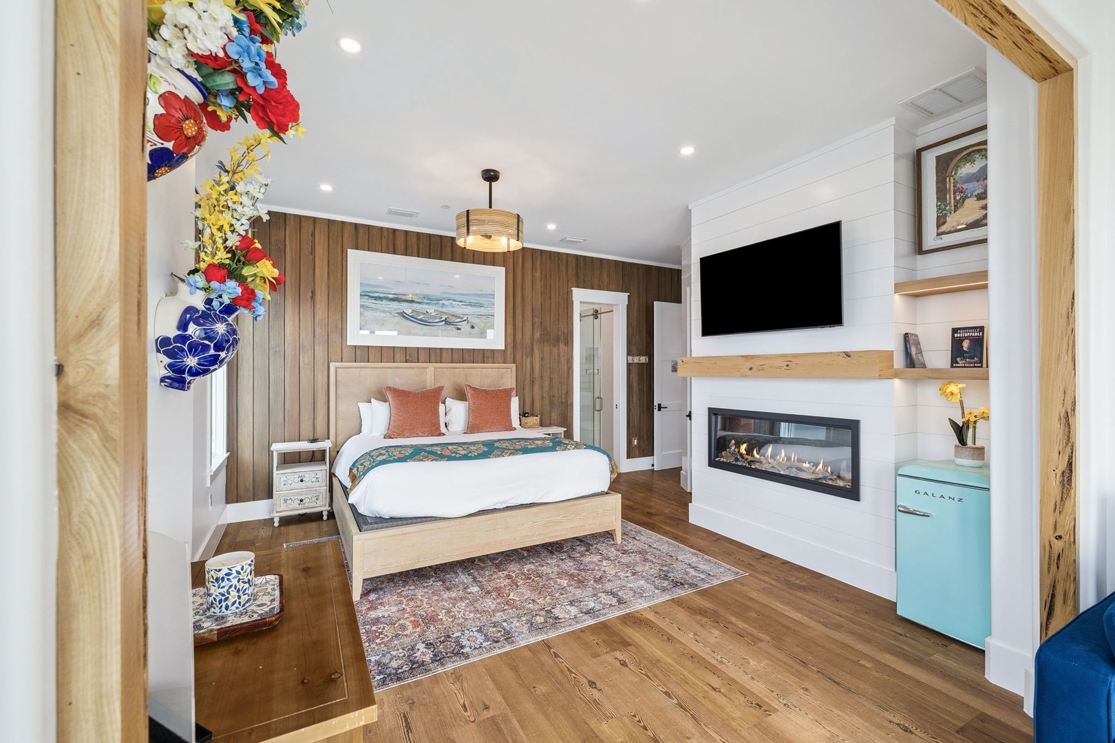 Your stylish bedroom features a cozy fireplace, large TV, and charming coastal artwork for perfect relaxation.