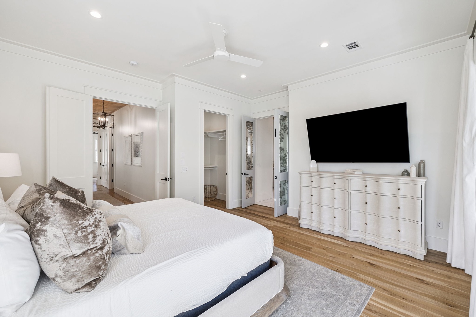 Unwind in your serene bedroom with crisp white linens, elegant furnishings, and modern entertainment—perfect for peaceful nights and lazy mornings.