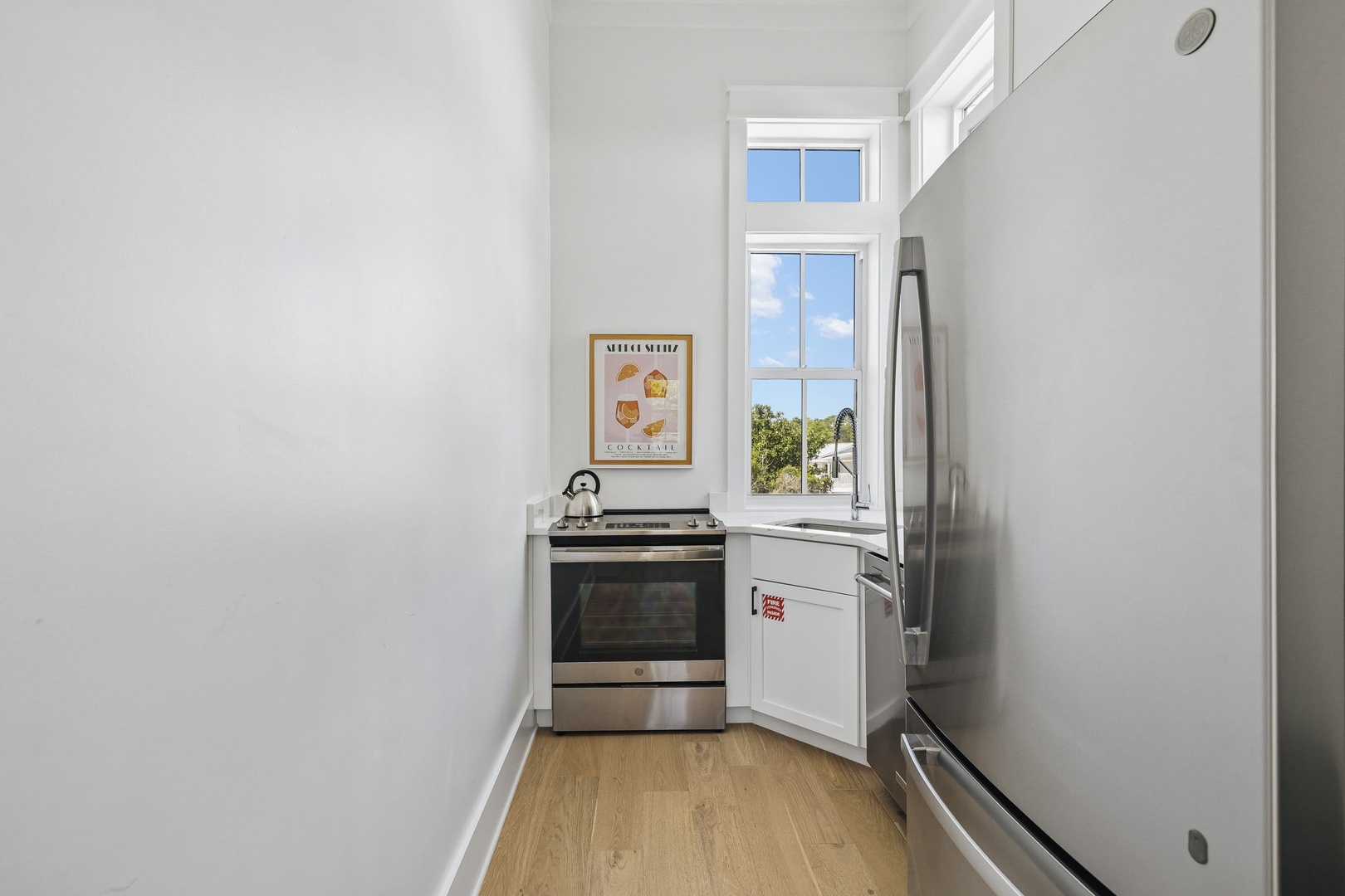 Your compact kitchen has everything you need to cook up a feast. Sunlight streams through the window while you prep meals, with a full stove, oven, and fridge ready for your culinary adventures.